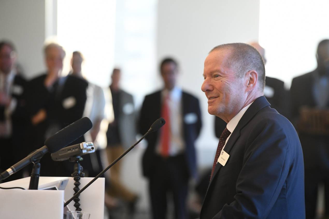 A person in a suit standing at a podiumDescription automatically generated